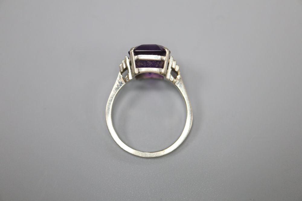 An Art Deco style 9ct white metal and emerald cut amethyst set dress ring, with stepped shoulders, size P, gross 3.8 grams.